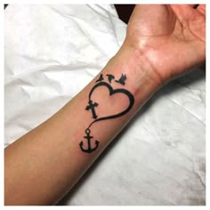 a woman's arm with an anchor and heart tattoo on the left side of her wrist