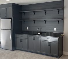 an empty kitchen with gray cabinets and black counter tops, along with stainless steel appliances