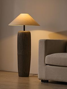 a lamp sitting on top of a wooden floor next to a couch