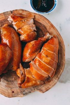 two pieces of chicken sitting on top of a wooden platter next to a cup of coffee