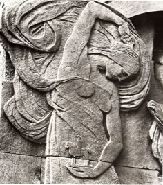 an ancient carving on the side of a building with two people standing next to it