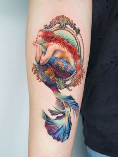 a woman's arm with a mermaid tattoo on it