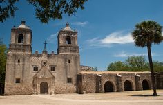 an old stone church with two towers and palm trees in the foreground on a sunny day