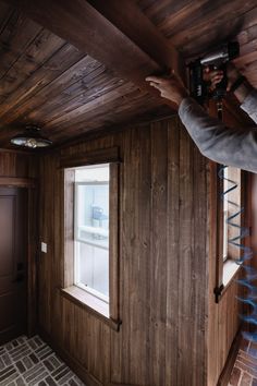 a man is taking a photo of the inside of a house with wood paneling