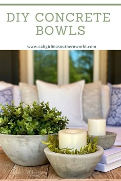 a table topped with two white bowls filled with plants and candles on top of it