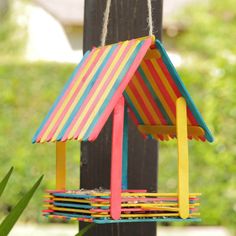 a bird house made out of popsicle sticks is hanging from a post with the words diy popsicle houses on it