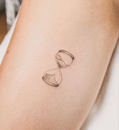 a woman's arm with a small hourglass tattoo on the left side of her body