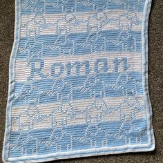 a blue and white afghan sitting on top of a carpet next to a pillow with the word'love'written across it