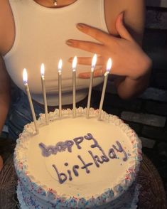 a woman holding a birthday cake with lit candles