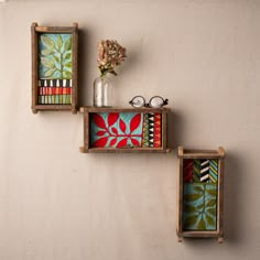 three wooden boxes with colorful designs on them and some flowers in the vase next to them