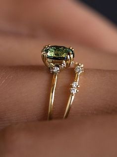 a close up of a person's hand wearing a ring with a green stone on it