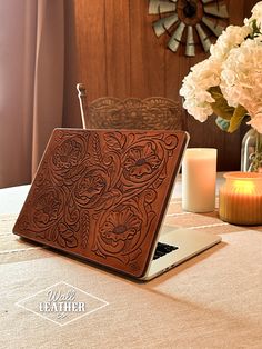 an open laptop computer sitting on top of a table next to a vase with flowers