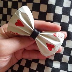 a hand holding a white bow with red hearts on it