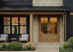 two chairs are sitting in front of a house with black siding and wood trimming