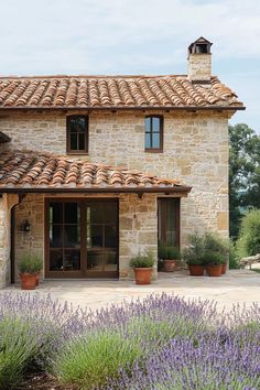 an old stone house with potted plants and lavender