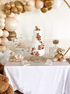 a table topped with a cake and lots of balloons