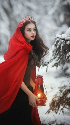 a woman in a red cloak holding a lantern