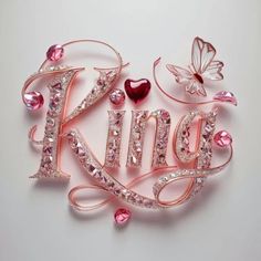 a pink brooch with the word king written in it's center surrounded by jewels and butterflies