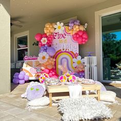 a table set up for a birthday party with balloons and decorations on the outside wall