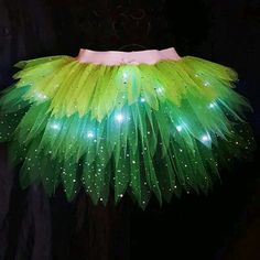 a green and white tutu skirt with lights on it's bottom, hanging from a black wall