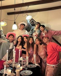 a group of people standing around a table with plates and candles in front of them