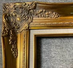 an ornate gold frame with flowers and leaves on the edge is sitting on a carpeted floor