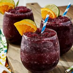 two glasses filled with smoothie and garnished with orange slices on a wooden cutting board