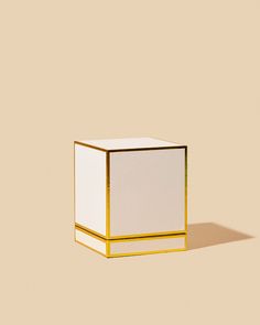 a white and gold box sitting on top of a brown floor next to a wall