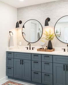 a bathroom with two round mirrors on the wall and double sinks in front of them