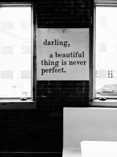 a black and white photo with a sign in the window that says, daring a beautiful thing is never perfect