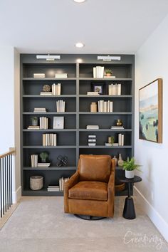 a living room filled with lots of bookshelves next to a chair and table