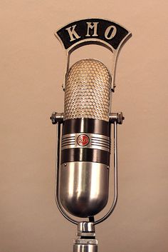 an old fashioned microphone with the word kmo on it's side and in front of a tan background