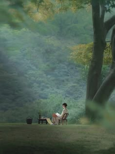 a woman sitting in a chair under a tree