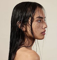 a woman with freckles on her body and wet hair looking off to the side