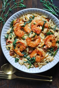 pasta with shrimp, spinach and sun dried tomatoes in a white bowl on a wooden table