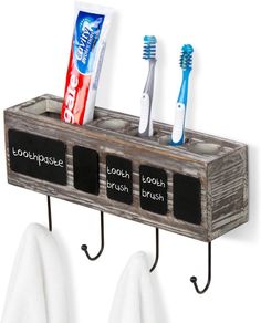 three toothbrushes and two toothpaste holders on hooks