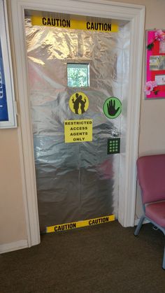 a door with some signs on it and a chair in front of the door that says caution