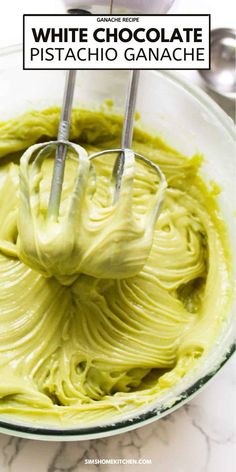 white chocolate and pistachio ganache in a glass bowl with two beaters