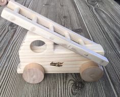 a wooden toy truck sitting on top of a wooden table next to a pair of scissors