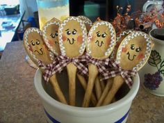 five wooden spoons with faces on them in a cup