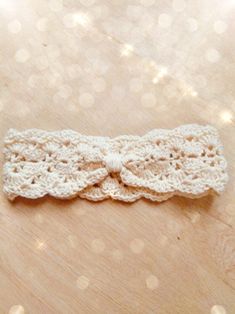 a white crocheted headband with a bow on it sitting on a table