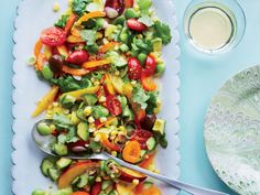 a plate full of vegetables on top of a table next to a cup and spoon