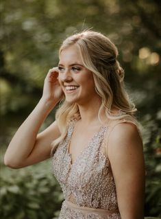 a woman in a dress smiles as she poses for the camera with her hand on her head