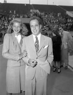 a man and woman standing next to each other in front of a crowd at a baseball game