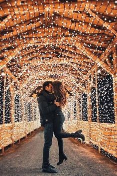 a man and woman kissing under an archway covered in lights