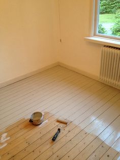 an empty room with a bowl and brush on the floor next to a radiator