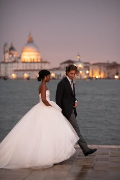 a bride and groom walking by the water at sunset in venice, italy on their wedding day