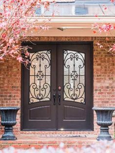 the front door to a house with two planters in front of it and an iron gate