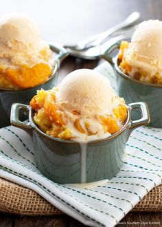 three bowls filled with ice cream on top of a cloth next to two spoons