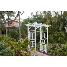 a white garden arbor in the middle of some trees